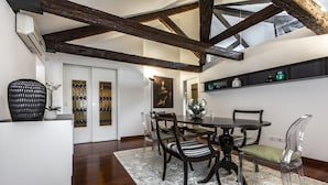 A dining area with a wooden table, chairs, and a rug. There is a staircase leading to an upper level. - San Pantalon Luxury Penthouse R&R (Venecia)