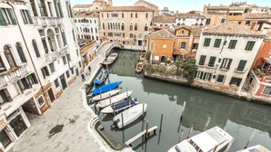 A canal with boats docked, surrounded by historic buildings with arched windows and balconies. - San Pantalon Luxury Penthouse R&R (Venecia)