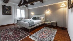 A bedroom with a large bed, two bedside tables, a floor lamp, and a window with curtains. - San Pantalon Luxury Penthouse R&R (Venecia)