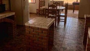 A kitchen with a brick island, a dining table with chairs, a refrigerator, and a view of the beach. - La Haciendita Beachfront Home + Private Pool (Ensenada)