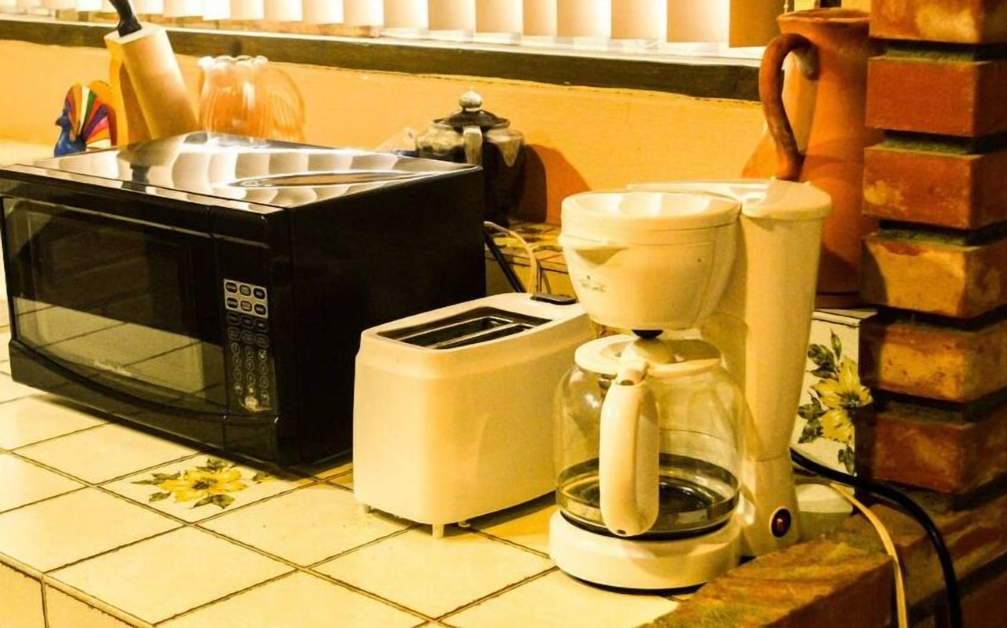 A kitchen with a microwave, toaster, and coffee maker on a tiled countertop.