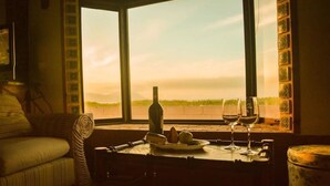 A cozy room with a view of the horizon, a table with a bottle and glasses, and a plate with fruits. - La Haciendita Beachfront Home + Private Pool (Ensenada)