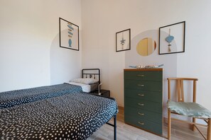 A bedroom with a bed, a dresser, a chair, and wall art. - Charming Villetta Lelù with Garden and Terrace by the Sea (Villasimius)
