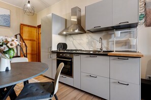 A modern kitchen with a stove, oven, and marble backsplash. - Lelu' a Welcoming End-of-Terrace House with a Private Garden and Terrace (Villasimius)