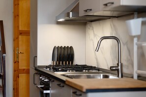 A kitchen with a gas stove, a sink, and a marble backsplash. - Charming Villetta Lelù with Garden and Terrace by the Sea (Villasimius)