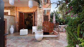 A courtyard with stone flooring, a wooden gate, and a white table with chairs.