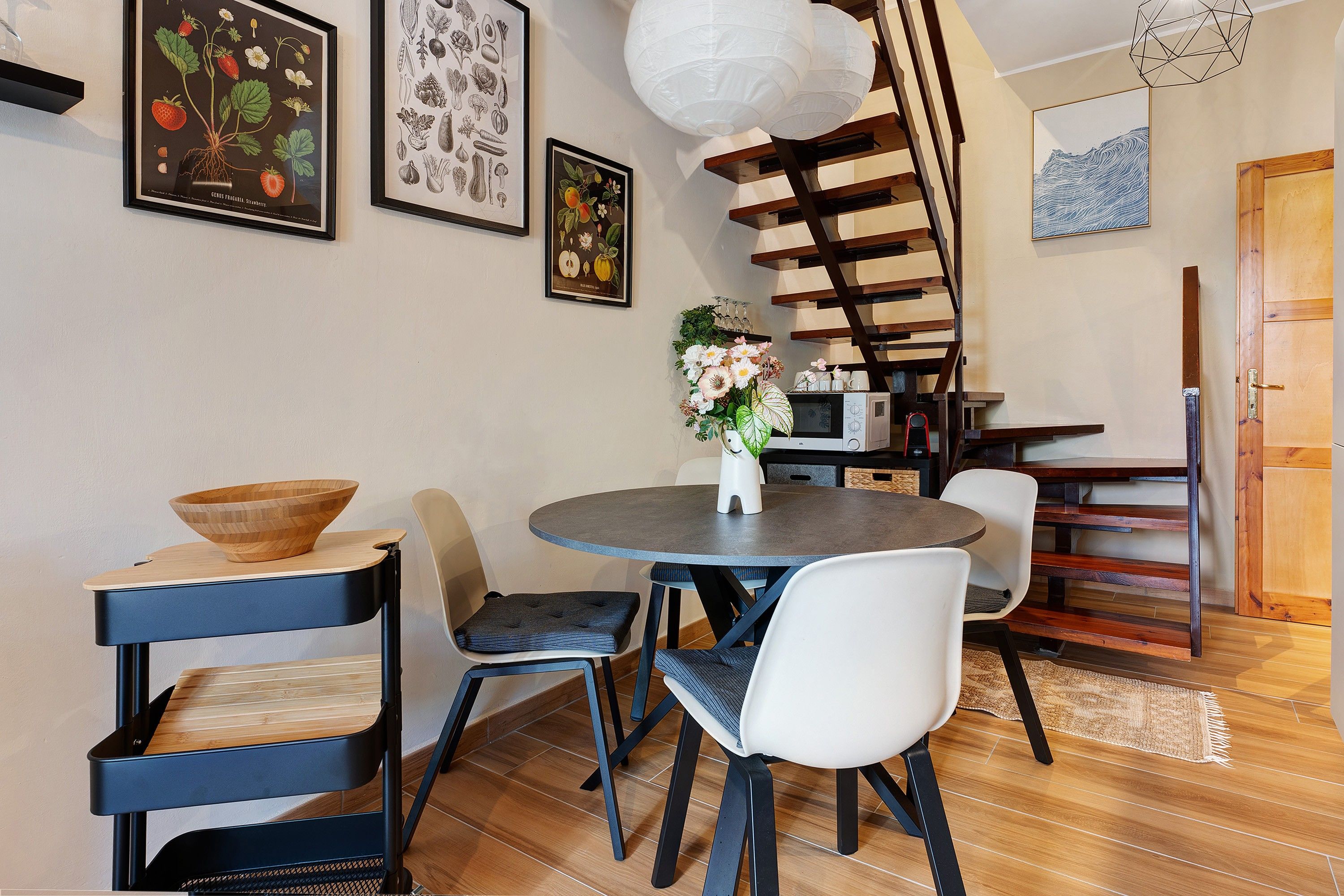 A dining area with a round table, chairs, and a vase of flowers.