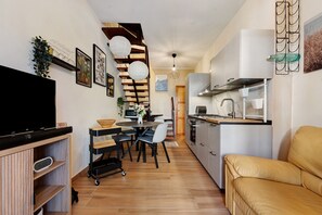 A modern kitchen with a dining area, a sofa, and a TV. - Charming Villetta Lelù with Garden and Terrace by the Sea (Villasimius)
