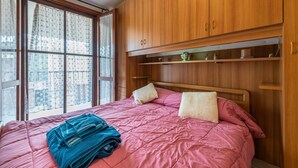 A bedroom with a bed, wooden wardrobe, and a window with curtains. - Charming Villetta Lelù with Garden and Terrace by the Sea (Villasimius)