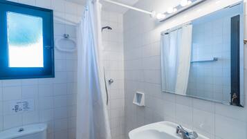 Un baño con inodoro, lavamanos, ducha y espejo.