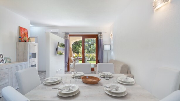 A dining area with a table set for six, a bowl, and chairs. - Modern Apartment with Air Conditioning and Garden; Pets Allowed (BUDONI)