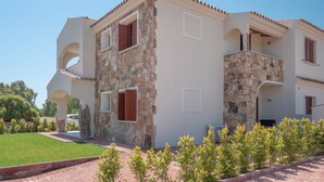 A two-story building with stone walls, a balcony, and a clear sky. - Modern Apartment with Air Conditioning and Garden; Pets Allowed (BUDONI)