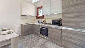 A modern kitchen with a built-in oven, a microwave, and a gas stove. - Modern Apartment with Air Conditioning and Garden; Pets Allowed (BUDONI)