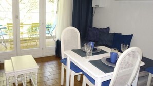 En matplats med ett bord, stolar och utsikt genom en glasdörr till en utomhusplats med sittmöbler.