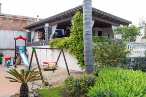 Ein Haus mit Terrasse, Schaukel und kleinem Garten.