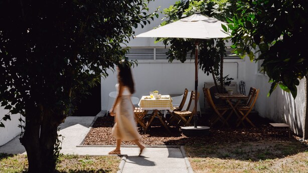 A patio area with a table and chairs under a large umbrella, surrounded by trees. - Feel Corporate Housing Marquês II (Oporto)