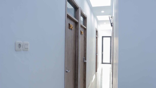 A corridor with a wooden door, a light switch, and a ceiling light. - Syariah Amethyst Cengkareng (Jakarta)