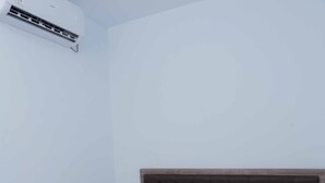 A room with a bed, a headboard, and an air conditioning unit mounted on the wall. - Syariah Amethyst Cengkareng (Jakarta)