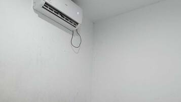 A room with a bed, a headboard, and an air conditioning unit mounted on the wall.