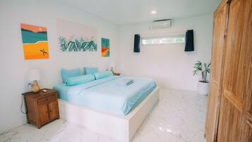 Un dormitorio con cama, mesita de noche, decoración en la pared y una planta en maceta.