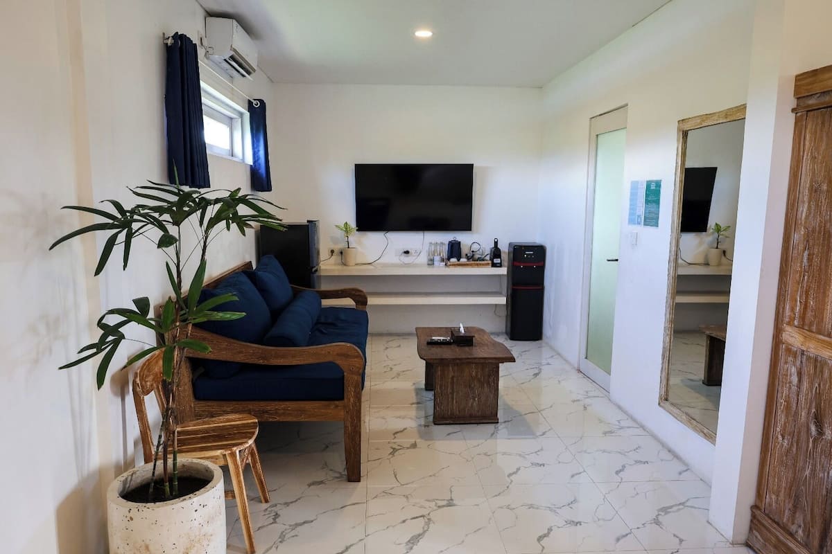 A living room with a sofa, a coffee table, a TV, and a refrigerator.