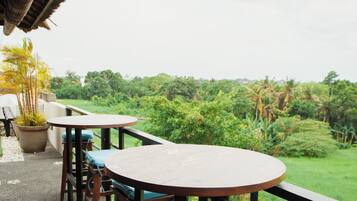 Une terrasse dotée de mobilier en bois et offrant une vue sur un paysage luxuriant.