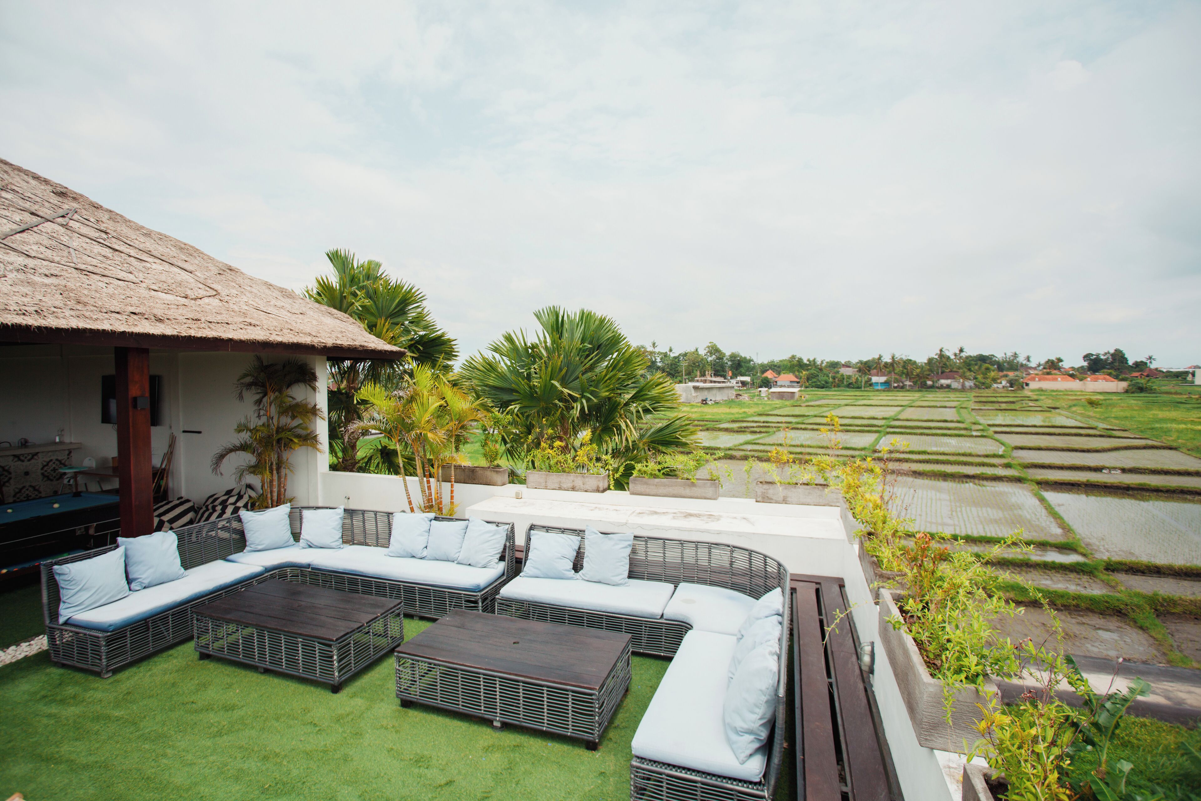 A rooftop lounge with a thatched roof, a sectional sofa, and a coffee table.