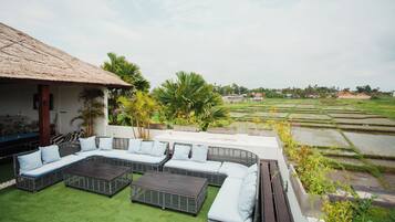 A rooftop lounge with a thatched roof, a sectional sofa, and a coffee table.