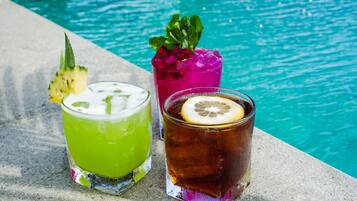 Three drinks by a poolside with a clear blue pool in the background.