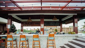 A bar area with wooden stools, a Christmas tree, and a chalkboard menu. - The Swell - Hostel - Adults Only (Tabanan)