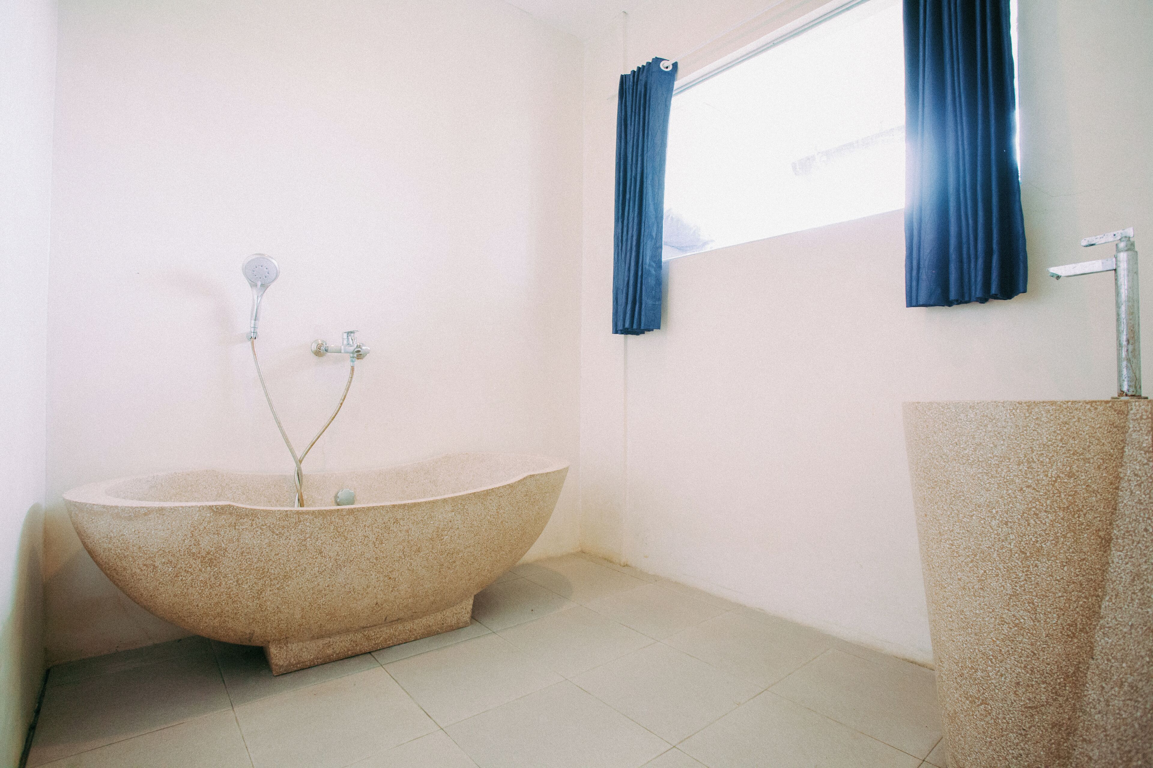 A bathroom with a freestanding bathtub, a window with curtains, and a towel rack.