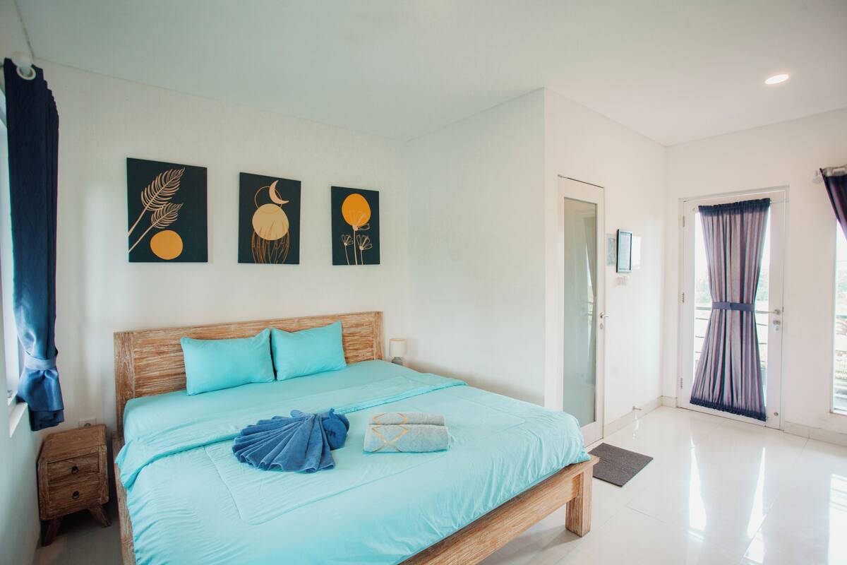 A bedroom with a bed, a nightstand, and artwork on the wall.