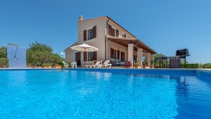 Ein Haus mit Schwimmbad, Gartenmöbeln und Grillplatz.