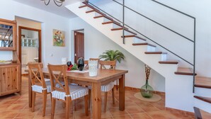 Ein Essbereich mit Holztisch und Stühlen, eine Treppe mit Holzstufen und Metallgeländern sowie ein Blumentopf.