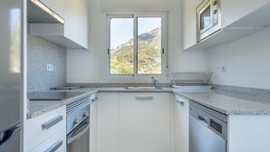 Una cucina moderna con una finestra, elettrodomestici in acciaio inossidabile e un piano di lavoro in granito.
