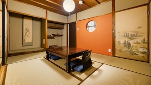Une pièce de style japonais traditionnel, avec un sol recouvert de tatamis, une petite table en bois et un paravent shoji orné d’un paysage.