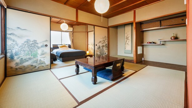 Une pièce de style japonais traditionnel, avec un sol recouvert de tatamis, une basse table en bois et des portes coulissantes ornées de motifs artistiques.