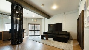 Un salon moderne avec un canapé en cuir noir, une table basse et un grand pilier décoratif noir.