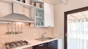 A kitchen with a gas stove, stainless steel sink, and wooden cabinets.