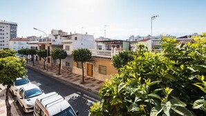 Una calle residencial con coches aparcados, árboles y edificios con balcones.
