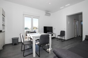 Ein modernes Wohnzimmer mit Essbereich, Flachbildfernseher und einer Couch.