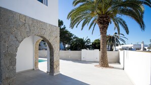 A modern building with a stone archway, a palm tree, and a clear blue sky.