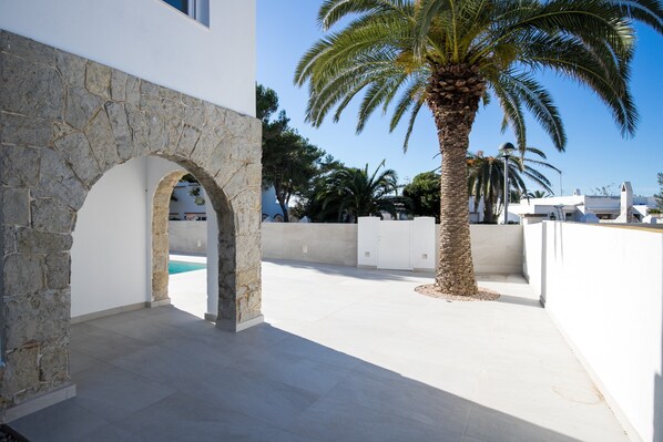 A modern building with a stone archway, a palm tree, and a clear blue sky.