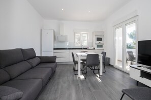 Un espacio de estar moderno con un sofá, una mesa de comedor, sillas, un televisor y una cocina.