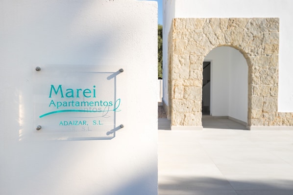 A sign for 'Marei Apartamentos' with a stone archway in the background.