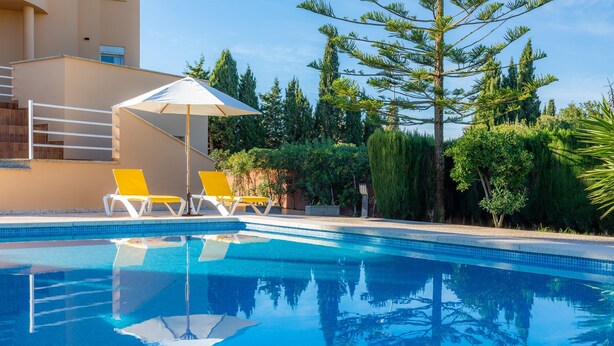 A swimming pool with clear blue water, two yellow lounge chairs, and a white umbrella. - Villa With Pool in Idyllic Location - Ca Na Xisca (Sa Coma)