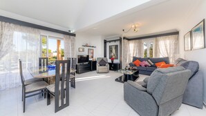 A modern living room with a dining area, a sofa set, a TV, and a fireplace. - Villa With Pool in Idyllic Location - Ca Na Xisca (Sa Coma)