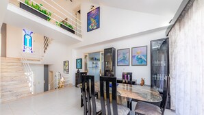 A dining area with a marble table and black chairs, a staircase with white railings, and a glass door leading to a balcony. - Villa With Pool in Idyllic Location - Ca Na Xisca (Sa Coma)