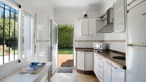 Une cuisine moderne avec des meubles blancs, un four à micro-ondes et un four encastré.