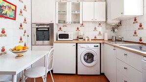 A compact kitchen with a microwave, oven, washing machine, and a sink.